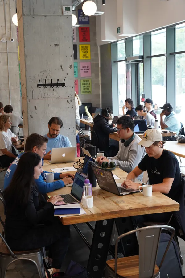 Members coworking at a long table by the window.